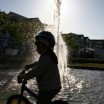 Kleiner Junge mit Fahrrad am Springbrunnen